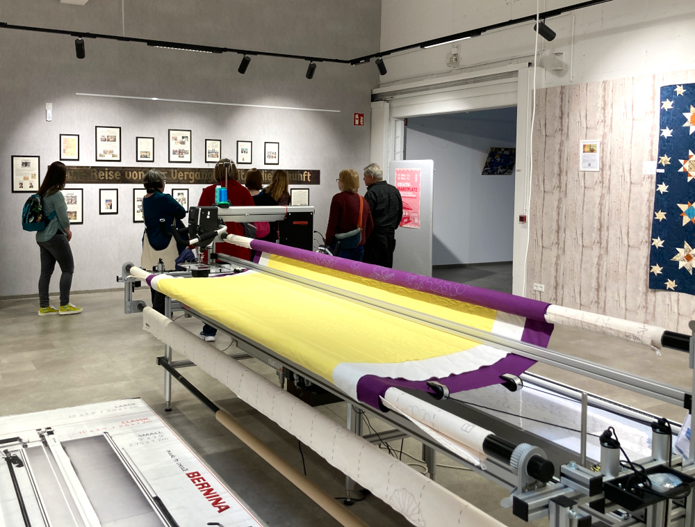 Gruppenführung durch das Ladengeschäft Nähwelt Flach. Im Vordergrund steht eine Longarm-Quiltmaschine.