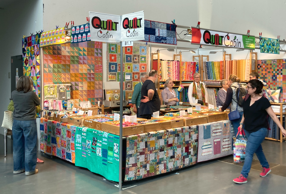 Der Stand von "Quilt Cabin" mit bunten Stoffen und Quilten auf der Nadelwelt in Karlsruhe 2026