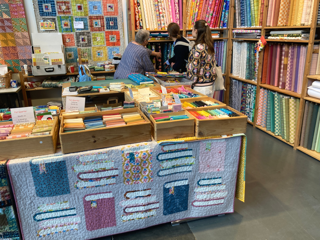 Der Stand von "Quilt Cabin" mit bunten Stoffen und Quilten auf der Nadelwelt in Karlsruhe 2026